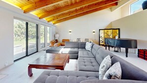 A spacious living room with a large sectional sofa, a wooden coffee table, and a grand piano. - Sea Ranch 2BR ocean-view home near the golf course & Bluff Trail (Sea Ranch)