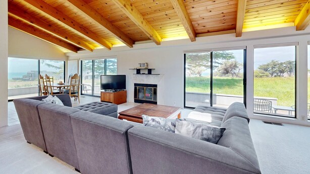 A spacious living area with a large sofa, a wooden coffee table, a flat-screen TV, and a fireplace. - Sea Ranch 2BR ocean-view home near the golf course & Bluff Trail (Sea Ranch)
