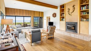 Ein modernes Wohnzimmer mit Klavier, Sofa, Fernseher, Kamin und Bücherregalen.