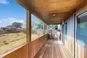 A wooden deck with a view of a backyard and a house. - Sea Ranch 4BR home with hot tub & ocean views near Shell Beach (Sea Ranch)