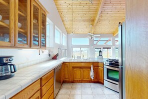 A kitchen with wooden cabinets, a built-in oven, and a coffee maker. - Ocean-view blufftop home with courtyard on the meadow, dogs welcome (Sea Ranch)