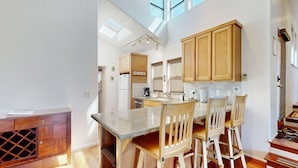 Una cocina moderna con armarios de madera, encimera de granito y comedor con sillas de madera.