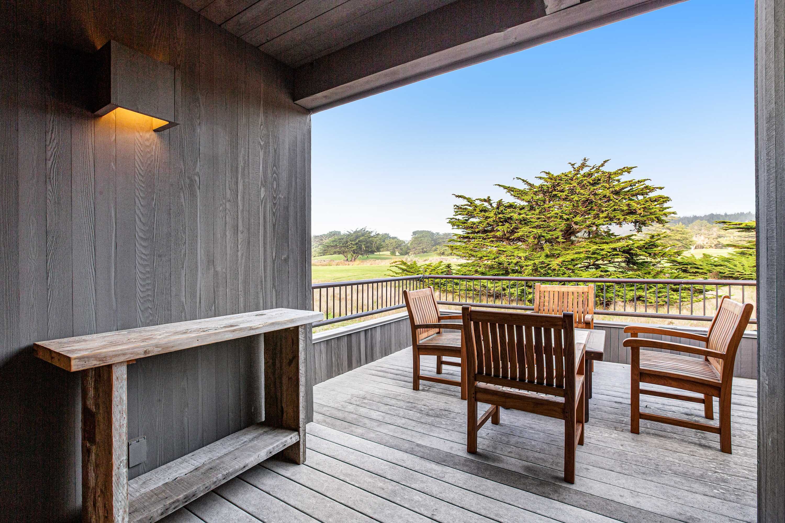 Eine Holzterrasse mit Bank und Stühlen mit Blick auf einen angelegten Garten.
