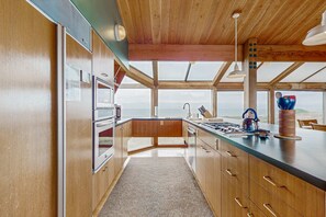 Eine moderne Küche mit Holzausstattung, einer großen Kochinsel und Blick durch die Fenster.
