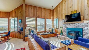 A wooden interior with a fireplace, seating area, and large windows.