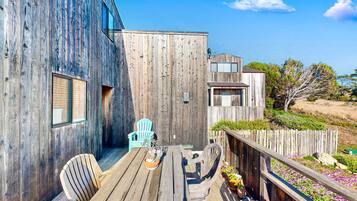 A wooden deck with a table and chairs, a blue chair, and a flower bed.