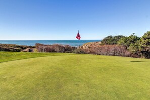 A golf course with a flag, a clear sky, and a view of the ocean. - Ocean-view meadow home with deck & grill near Black Point, dogs welcome (Sea Ranch)