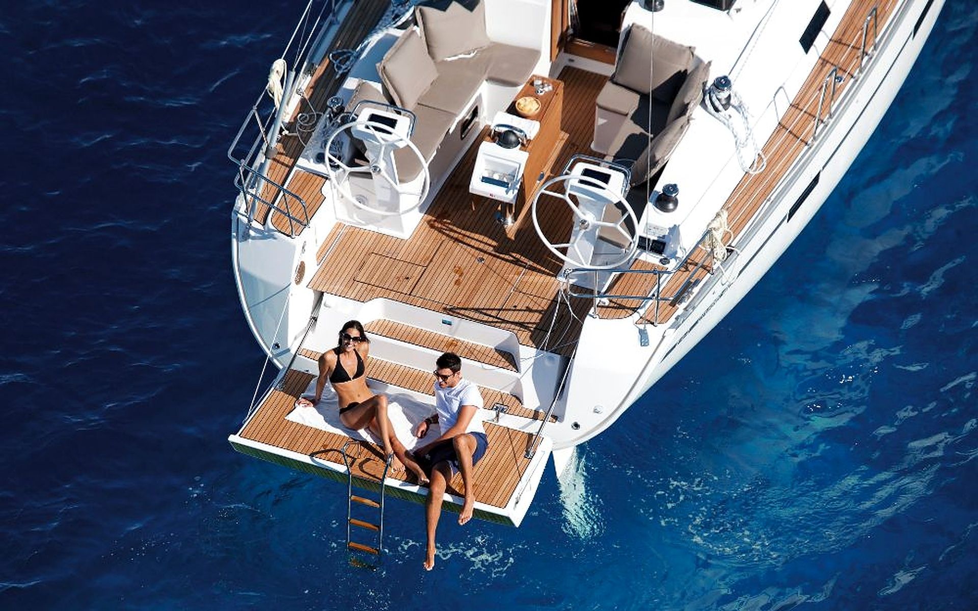 A yacht with a deck area featuring lounge chairs, a table, and a seating arrangement.