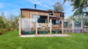 Une cabane en bois dotée d’une véranda en verre, d’une terrasse et d’une cheminée.