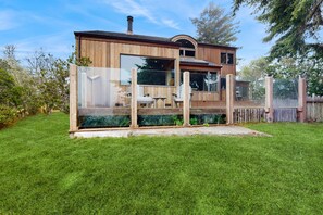 A wooden cabin with a glass enclosure, a deck, and a chimney. - Ocean-view home with fireplace & courtyard near Pebble Beach (Sea Ranch)