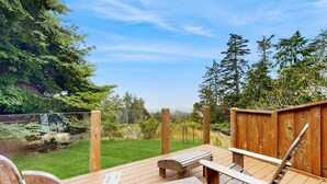 Une terrasse en bois avec un banc et une table, entourée d’une clôture en bois et d’arbres.