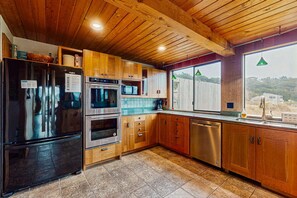 A modern kitchen with wooden cabinets, stainless steel appliances, and a large window. - Sea Ranch home with private hot tub near beach & playground (Sea Ranch)