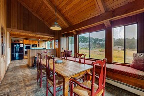 A wooden interior with a dining table, chairs, and a view through large windows. - Sea Ranch home with private hot tub near beach & playground (Sea Ranch)