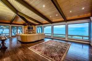 A spacious room with a large wooden ceiling, a beige sofa, a patterned rug, and a view of the ocean through large windows. - Blufftop home with hot tub & forever oceanfront views & private cottage (Gualala)