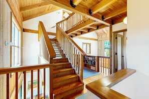 Eine Holztreppe mit Geländer, ein Bücherregal und eine Tür zu einem anderen Raum.
