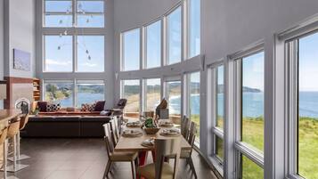 A spacious dining area with a large table, chairs, and a view of the ocean.