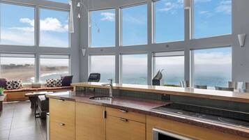 A modern kitchen with large windows, a built-in oven, and a view of the sea.