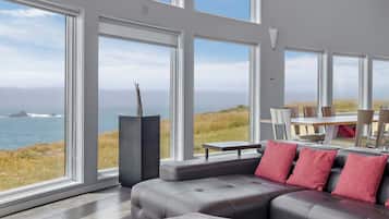 A modern living room with large windows, a sectional sofa, and a wooden coffee table.