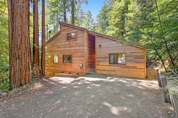 Eine Holzhütte mit einem Hauseingang, einer kleinen Veranda und freiem Blick auf den umliegenden Wald.