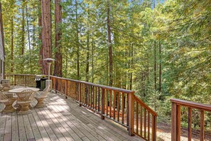 Eine Holzterrasse mit Korbmöbeln und einem Geländer mit Blick auf einen Wald.