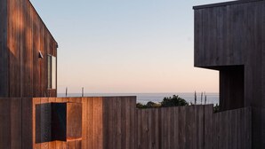 Een modern gebouw met een houten gevel en uitzicht op de oceaan.