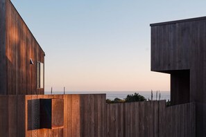 Ein modernes Gebäude mit Holzfassade und Meerblick.