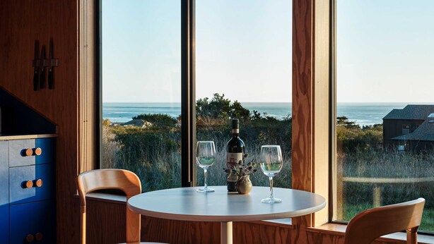 Een eetruimte met een tafel, stoelen en uitzicht op de oceaan.