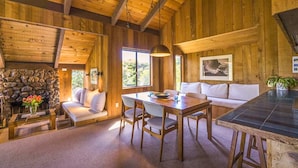 A wooden interior with a stone fireplace, a dining area, and a sofa. - Rare Ocean Views & Sea Ranch Magic on the Mendocino Coast (Sea Ranch)