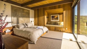 A bedroom with a large bed, a wooden ceiling, a window with a view, and a painting on the wall. - Rare Ocean Views & Sea Ranch Magic on the Mendocino Coast (Sea Ranch)