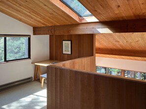 A room with a sloped ceiling, wooden paneling, a desk, a chair, and a framed picture on the wall. - Sea Ranch 2BR timber-frame home with hot tub near Stengel Beach (Sea Ranch)