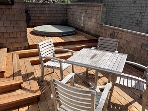 A wooden deck with a round table and four chairs, surrounded by a brick wall. - Sea Ranch 2BR timber-frame home with hot tub near Stengel Beach (Sea Ranch)