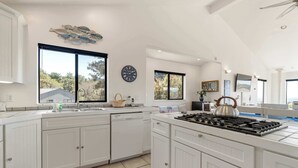 Una cocina moderna con armarios blancos, una isla grande con estufa y un reloj en la pared.