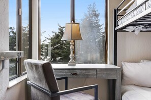 A bunk bed with a white mattress, a desk with a lamp, and a chair. - Sea Ranch meadow home with fireplace & panoramic ocean views (Sea Ranch)