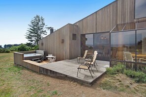 A modern building with a wooden deck, outdoor seating, and a hot tub. - Sea Ranch 2BR Don Jacobs-designed home with hot tub near Shell Beach (Sea Ranch)