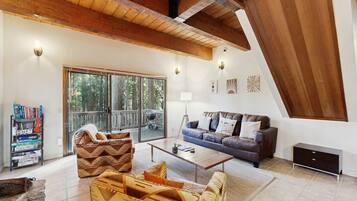 A spacious living room with a high ceiling, a sofa, a coffee table, and a bookshelf.