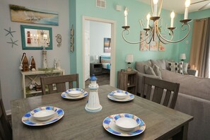 A dining area with a table set for four, a chandelier, and nautical-themed decor. - Three Bed Resort Condo Near Disney (Kissimmee)