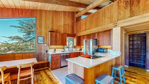 Un intérieur en bois comprenant une cuisine, un coin repas et de grandes fenêtres.