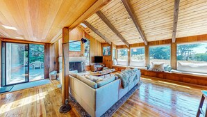 Un vaste espace de vie doté d’un grand canapé, de parquet et de grandes fenêtres offrant une vue sur l’extérieur.