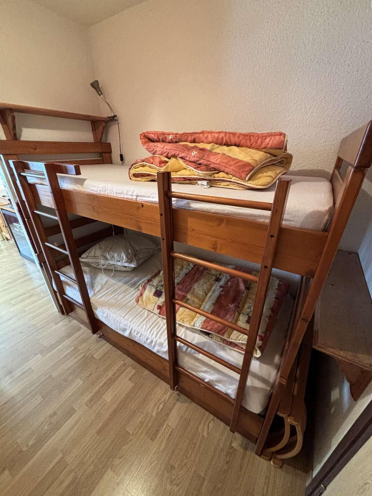 En våningssäng med en träram, en madrass och ett täcke.