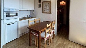 Ett kök med vita skåp, ett matbord i trä och stolar.