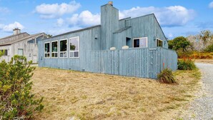 A modern building with a sloped roof, large windows, and a gravel driveway. - Sea Ranch 2BR home with private hot tub & game room — dog friendly (Sea Ranch)