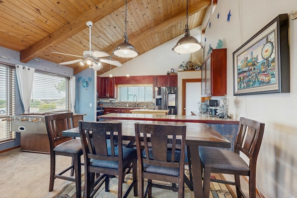 A spacious kitchen with wooden cabinets, a central island, and pendant lighting.
