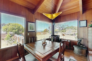 A wooden-paneled room with a dining table, chairs, a chandelier, and a statue. - Gualala 1BR + loft home with partial ocean views — walk to town (Gualala)