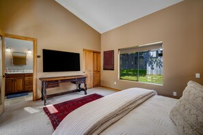 A bedroom with a bed, a desk, a TV, a window, and a bathroom. - Coastal Luxury: Chef Kitchen, Ocean Views, Hot Tub (Sea Ranch)