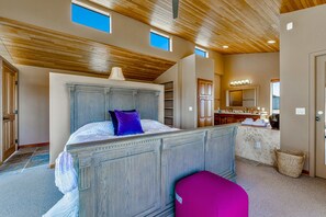 Un dormitorio con una cama grande, estanterías empotradas, un tocador con espejo y techo de madera.