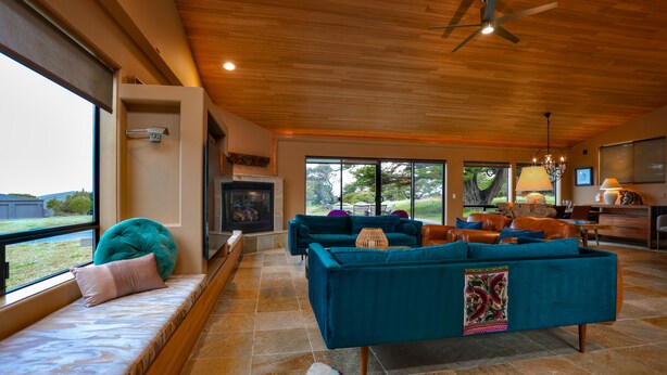 A spacious living room with a fireplace, large windows, and a view of the outdoors. - Coastal Luxury: Chef Kitchen, Ocean Views, Hot Tub (Sea Ranch)