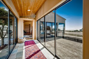 Un interior moderno con techo de madera, una puerta de vidrio que da al exterior y una alfombra con estampado en el suelo.