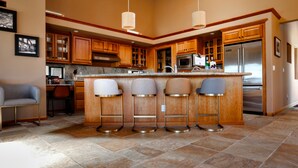 A modern kitchen with a central island, bar stools, wooden cabinets, stainless steel appliances, and pendant lighting. - Coastal Luxury: Chef Kitchen, Ocean Views, Hot Tub (Sea Ranch)