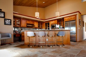A modern kitchen with a central island, bar stools, wooden cabinets, stainless steel appliances, and pendant lighting. - Coastal Luxury: Chef Kitchen, Ocean Views, Hot Tub (Sea Ranch)