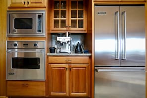 Una cocina con electrodomésticos de acero inoxidable, incluyendo un microondas, horno, cafetera y refrigerador.